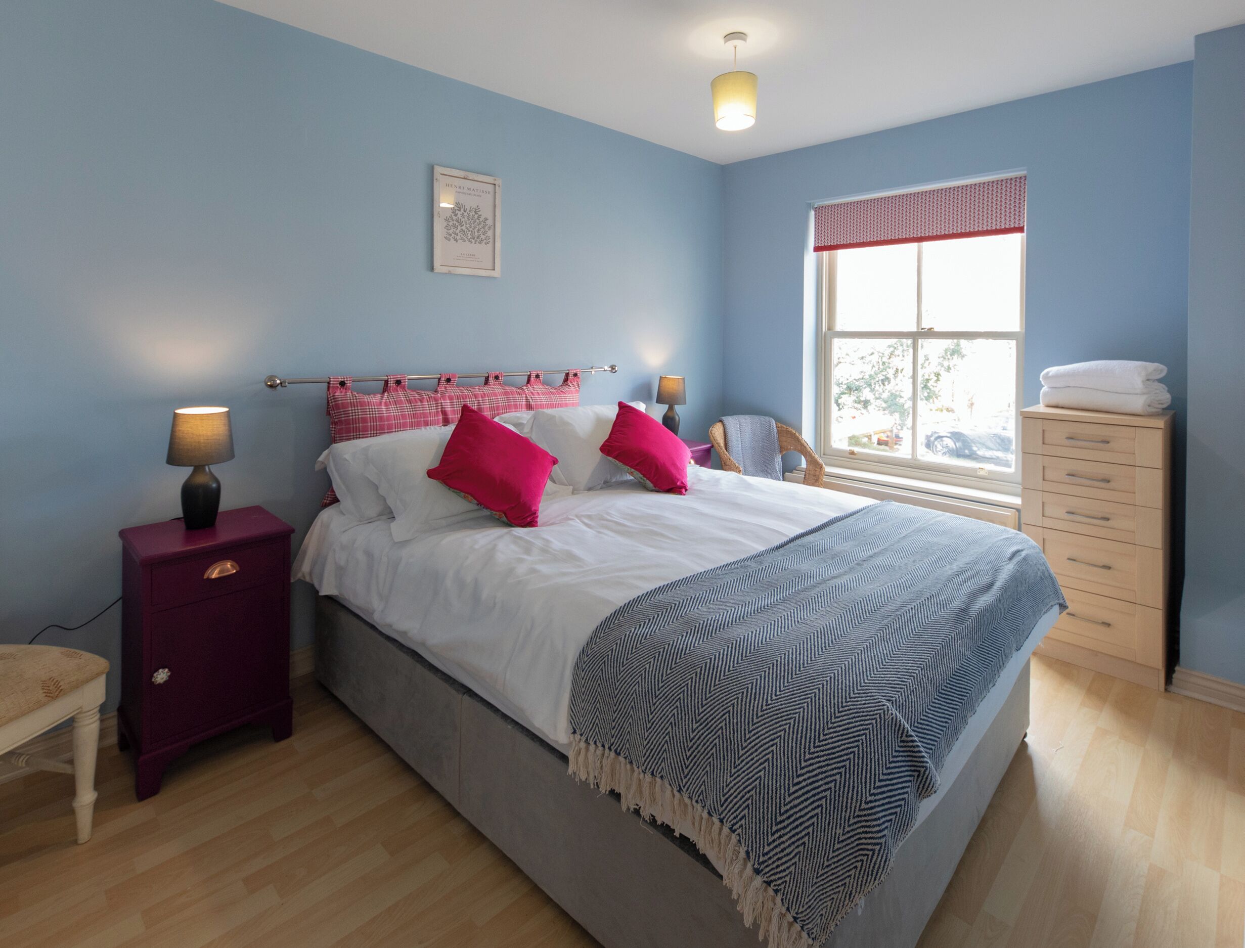 A bedroom with a bed, nightstands, a window, and a dresser.