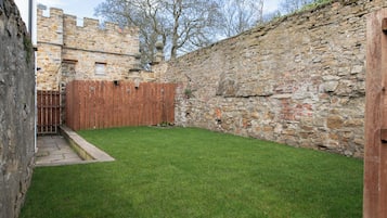 A stone wall, a wooden fence, and a grassy yard.