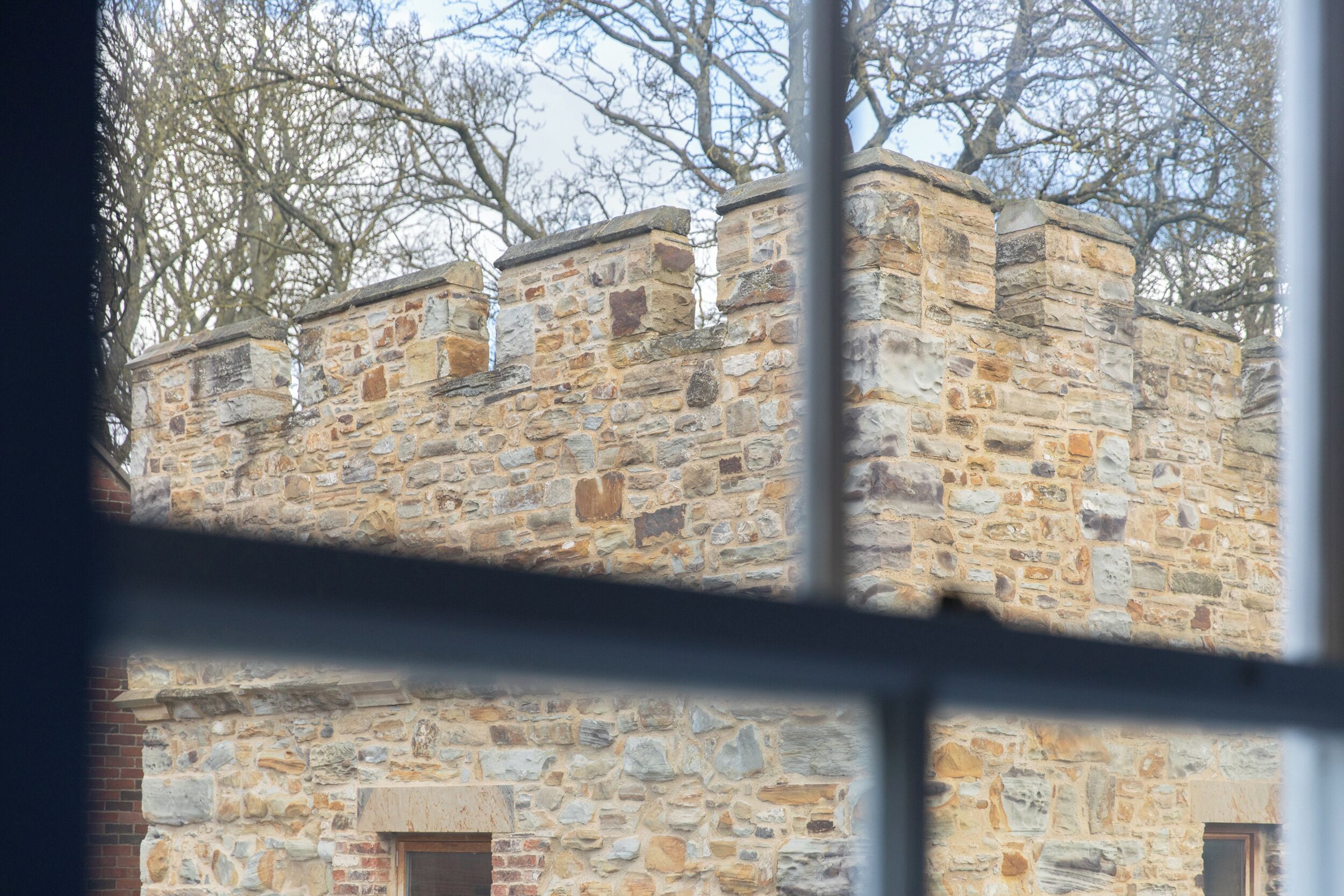 Un edificio de piedra con una ventana y una puerta, visto a través de un marco de ventana.
