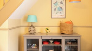 A corner with a grey cabinet, a blue lamp, a vase with yellow flowers, a woven basket, and a framed picture on the wall. - No 2 Townhouse (Bishop Auckland)