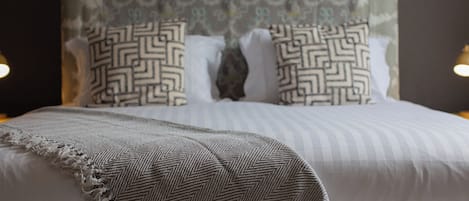 A neatly made bed with a patterned pillow, a striped blanket, and a headboard with a decorative design.