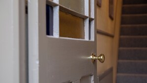 A white door with a brass doorknob and a window with a wooden frame. - No 2 Townhouse (Bishop Auckland)