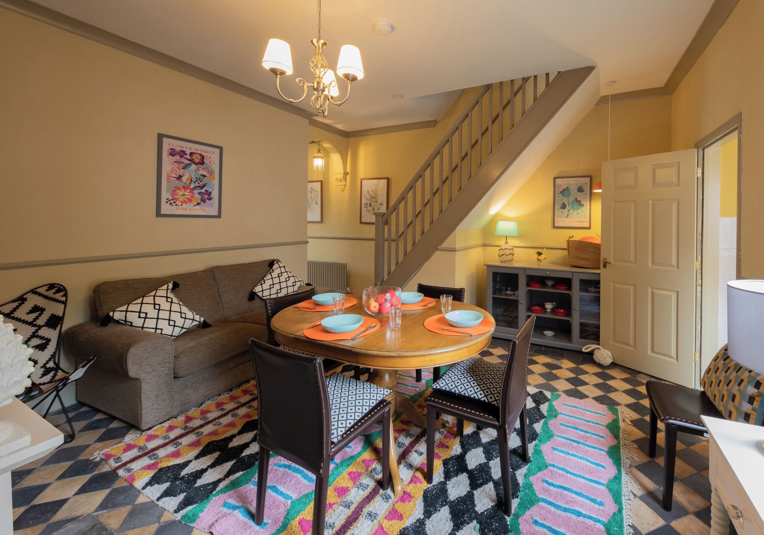 A dining area with a round table, chairs, a staircase, and a sofa.