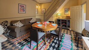 A dining area with a round table, chairs, a staircase, and a sofa. - No 2 Townhouse (Bishop Auckland)