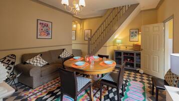 A dining area with a round table, chairs, a staircase, and a sofa.