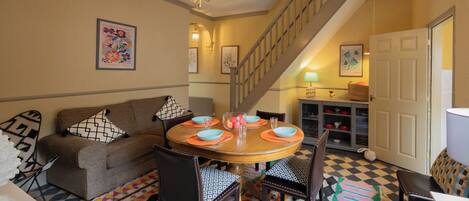 A dining area with a round table, chairs, a staircase, and a sofa.