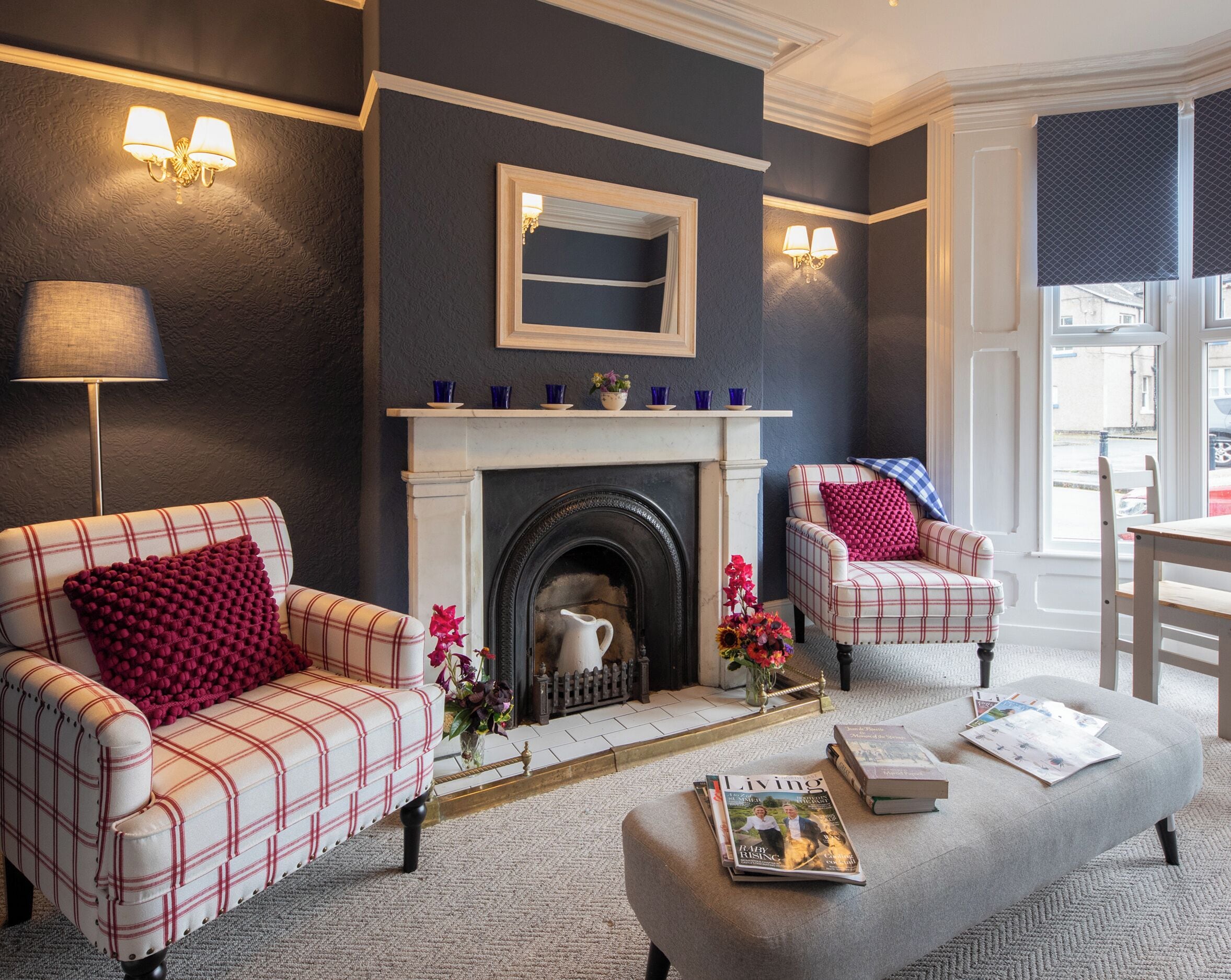 A living room with a fireplace, two armchairs, a sofa, a lamp, and a magazine on a coffee table.