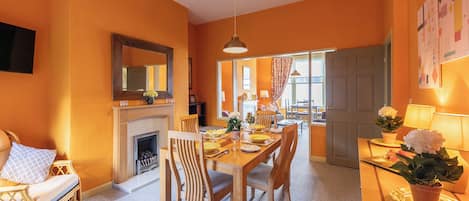 A dining area with a fireplace, wooden furniture, and a view into another room.