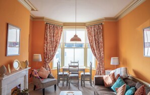 Ein Zimmer mit Kamin, Esstisch und einer Couch.