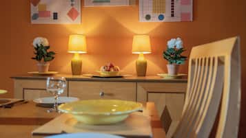 A dining table with yellow plates, two lamps, and potted plants.