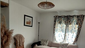 Una sala de estar con sofá, sillón, mesa de centro, lámpara de pie y lámpara colgante.