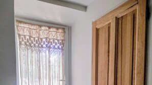 Una puerta de madera con manija de metal, un conjunto de escalones de concreto que conducen a una ventana con cortina decorada.