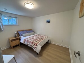 A bedroom with a bed, a nightstand, a window, and a door. - Cozy Bright Suite with Separate Entrance in Scarborough | Near Hospital (Toronto)