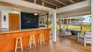 A wooden bar area with stools, a chalkboard with writing, and a view of the outdoors. - Welcome to Waters Edge, a true hidden gem on Little Gasparilla Island-where turquoise water, gentle breezes, and total relaxation replace traffic, noise, and stress (Placida)