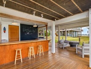 Eine Holztresnittbar mit Hockern, eine Kreidetafel mit Schrift und Blick ins Freie.