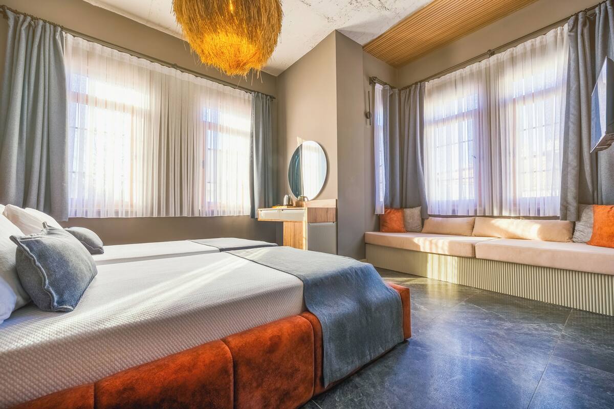 Ein modernes Hotelzimmer mit einem großen Bett, einer Sitzecke und einem großen Fenster mit Vorhängen.