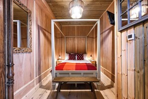 A wooden four-poster bed with a red and orange checkered bedspread, two bedside lamps, and a wooden ceiling with a modern light fixture. - Stylish Notting Hill Apartment (Greater London)