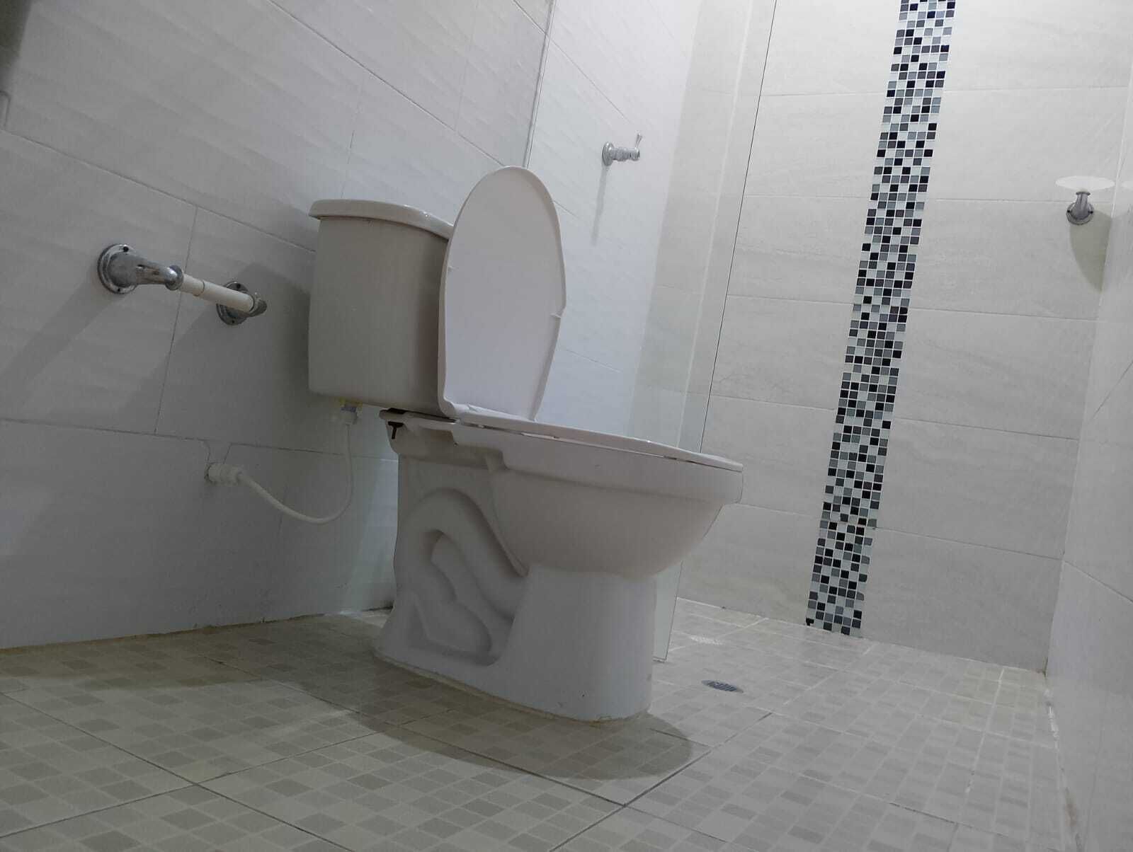A bathroom with a toilet, a shower, and tiled walls.