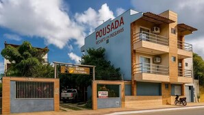 Un edificio con un cartel que dice 'POUSADA RECANTO 135 PASSAROS' y una entrada con portones.