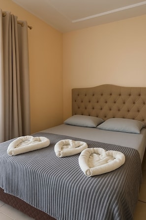 A hotel room with a bed, curtains, and a headboard.