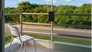 Un balcón con una silla, vista a una carretera y follaje.