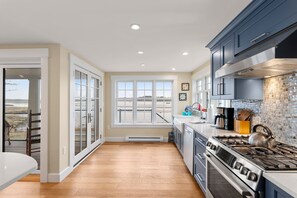 A kitchen with a large window, a stove, and a view of the outdoors.