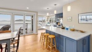 Una cocina moderna con una isla grande, taburetes de bar y vista al agua.