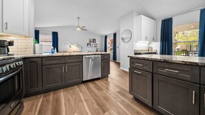 A modern kitchen with dark cabinets, a central island, and a built-in oven.