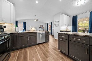 Une cuisine moderne avec des meubles de couleur sombre, un îlot central et un four encastré.