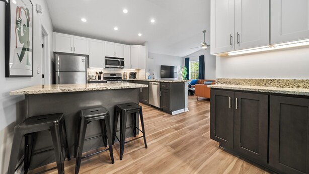 A modern kitchen with a central island, bar stools, and a dining area with a sofa.