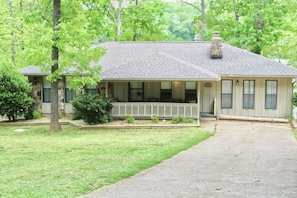 A two-story house with a front porch, stone foundation, and a chimney.