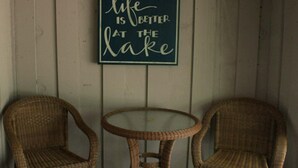 Twee rieten stoelen en een tafeltje tegen een houten wand met een motiverende quote.