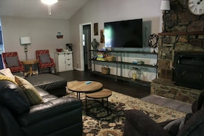 A living room with a sofa, two chairs, a TV, a fireplace, and a bookshelf.