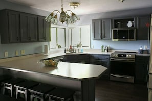 A modern kitchen with a large island, stainless steel appliances, and dark cabinetry.