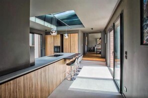 Une cuisine moderne dotée d’un îlot central, de luminaires suspendus et d’une verrière.
