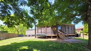 A backyard with a wooden deck, a trampoline, and a covered play area. - Relax in this 2-bedroom lakefront home. Shared dock. Kayaks. Pet friendly (Cadiz)