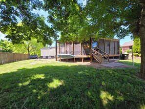 A backyard with a wooden deck, a trampoline, and a covered play area. - Relax in this 2-bedroom lakefront home. Shared dock. Kayaks. Pet friendly (Cadiz)
