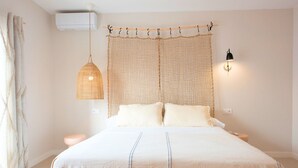 A bedroom with a bed, a hanging light, a wall-mounted lamp, and a window with curtains. - Villa Brisamar Azul | Caleta de Fuste | Golf Views | Heated Pool | Near Beach (Fuerteventura)