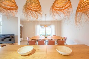 Un comedor con una mesa de madera, seis sillas y una lámpara colgante de fibras naturales.