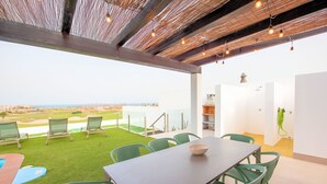 A rooftop terrace with a dining table, chairs, and a view of the landscape. - Villa Brisamar Azul | Caleta de Fuste | Golf Views | Heated Pool | Near Beach (Fuerteventura)