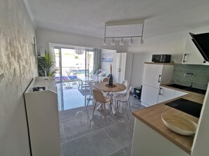 A modern kitchen with a dining area, a balcony with a view, and a small living space.