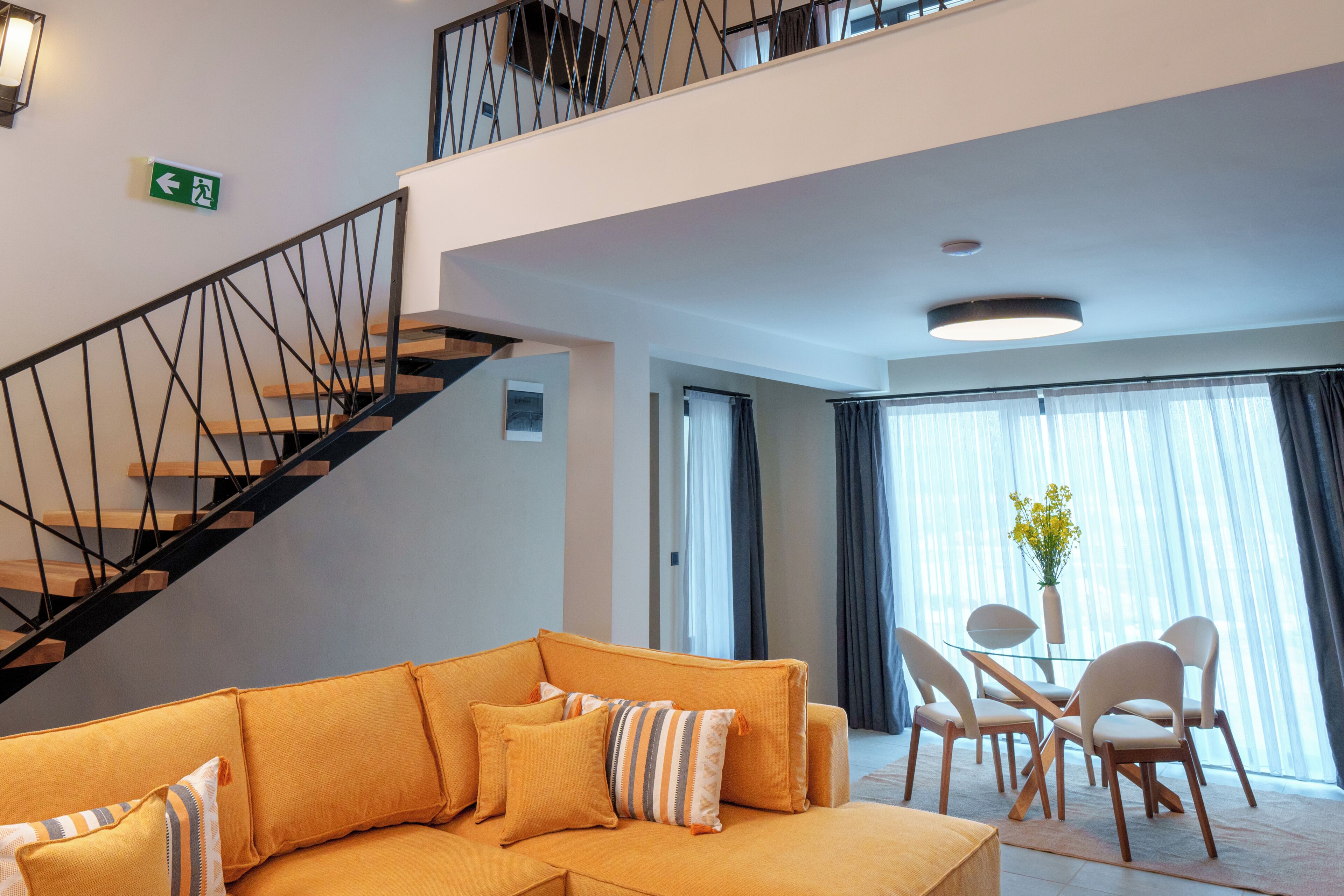 Un moderno vestíbulo de hotel con una escalera, un sofá, sillas y una mesa.