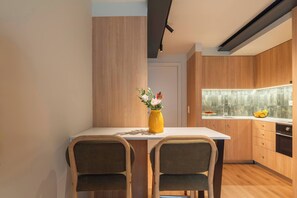 Una cucina moderna con mobili in legno, un piano di lavoro bianco e un vaso giallo con fiori.