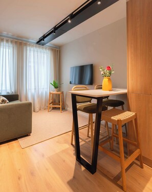 Un soggiorno moderno con un divano, un tavolo da pranzo con sedie, una TV a parete e un mobiletto in legno.