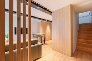 Ein modernes Interieur mit einer Treppe, Holzboden, einer Essecke mit Stühlen und einem Tisch sowie einem großen Kleiderschrank.