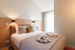 Quarto de hotel com cama, abajures, um serviço de café da manhã e uma janela com cortinas.