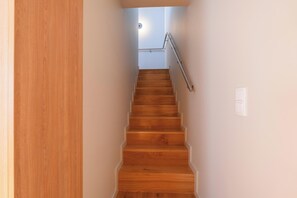Una scala in legno con ringhiera in metallo che conduce a un pianerottolo.