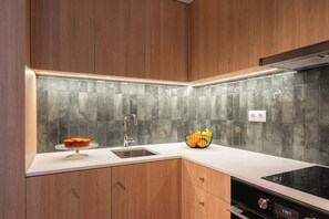 Uma cozinha moderna com armários de madeira, uma pia de aço inoxidável e painel de azulejos.