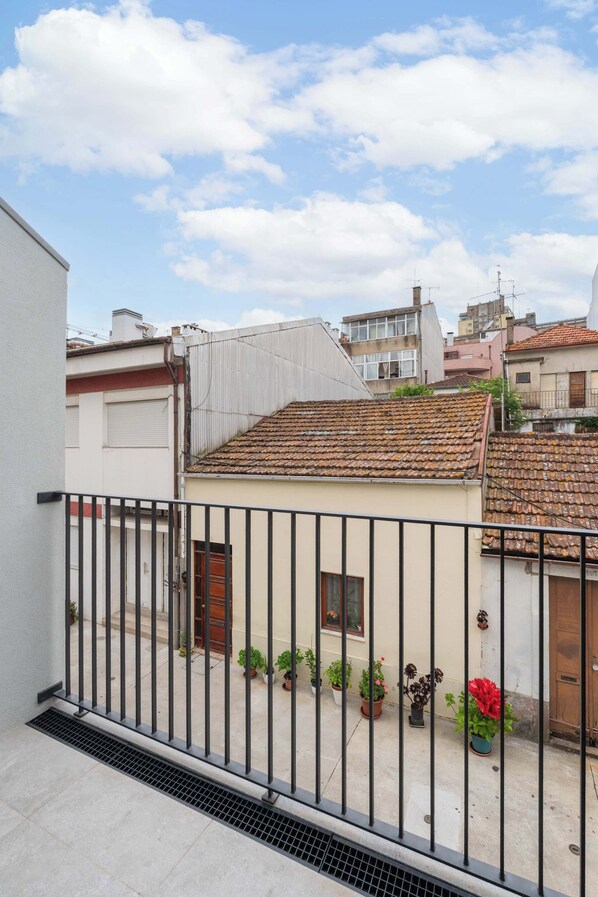 Uma área residencial com um pequeno edifício, vasos de plantas e uma cerca de metal.