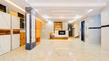 A hotel reception area with marble flooring, a reception desk, and a mural on the wall.